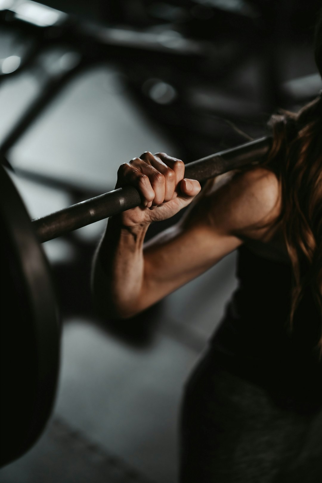 Coach lifting a loaded barbell in a dark gym